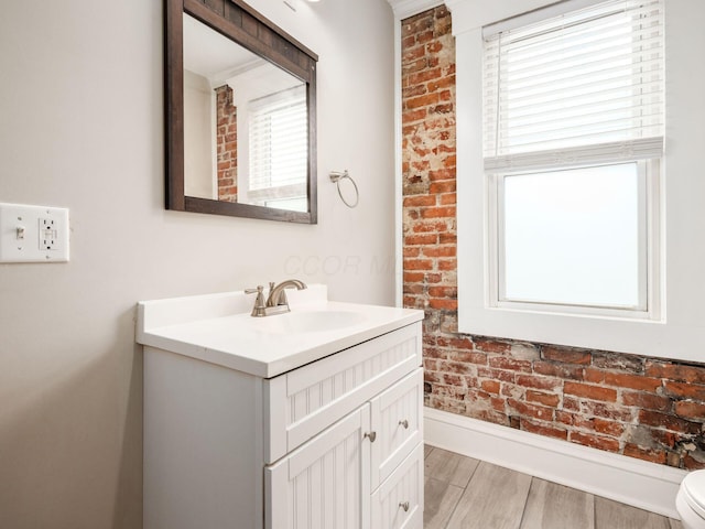 444 S 22nd St, Columbus, OH 43205 - bathroom featuring vanity, wood finished floors, toilet, brick wall, and baseboards