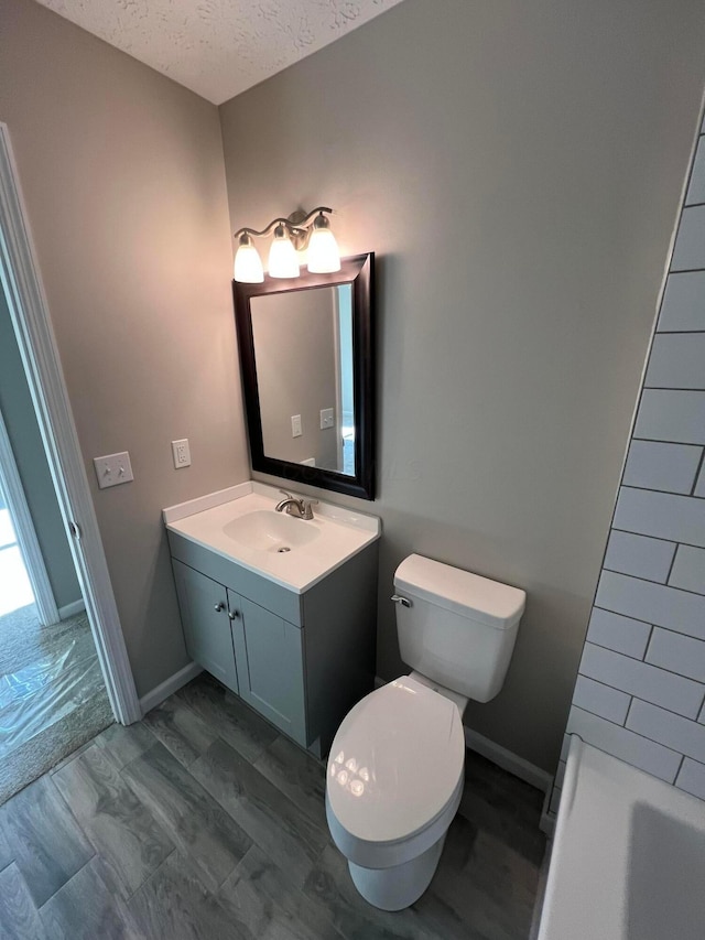 796 Village Park Dr, Powell, OH 43065 - bathroom with vanity, baseboards, a textured ceiling, toilet, and a tub to relax in
