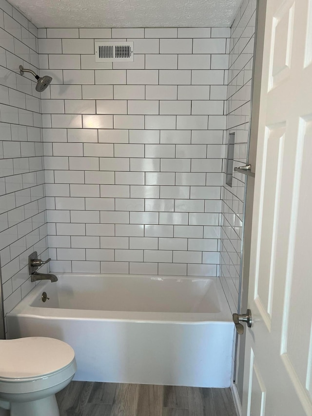 796 Village Park Dr, Powell, OH 43065 - bathroom with visible vents, toilet, shower / bathing tub combination, a textured ceiling, and wood finished floors