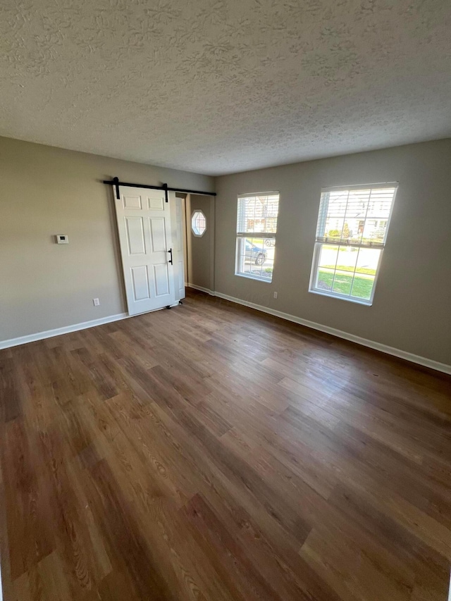 796 Village Park Dr, Powell, OH 43065 - spare room featuring a textured ceiling, baseboards, dark wood finished floors, and a barn door