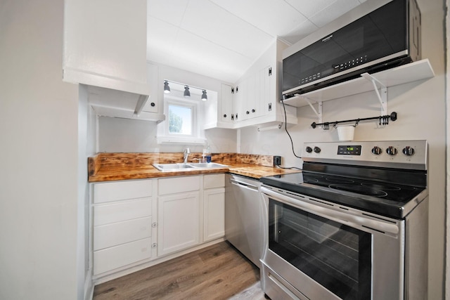 kitchen featuring a sink, butcher block counters, white cabinets, and stainless steel appliances