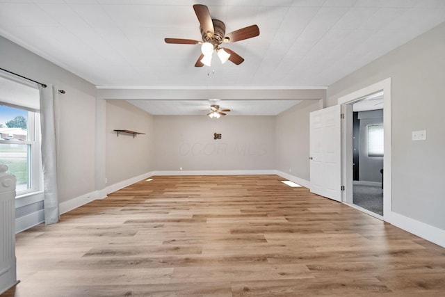 empty room with ceiling fan, light wood-type flooring, and baseboards