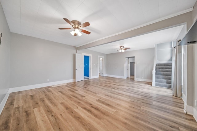 unfurnished living room with baseboards, a ceiling fan, light wood-style floors, crown molding, and stairs