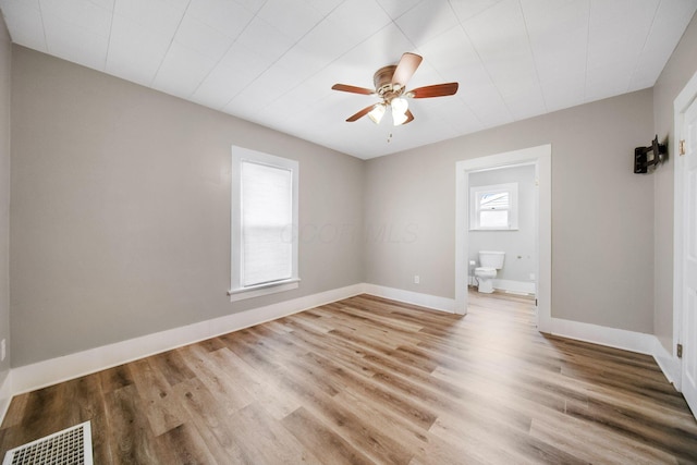 unfurnished bedroom with visible vents, baseboards, ensuite bathroom, ceiling fan, and light wood-style floors