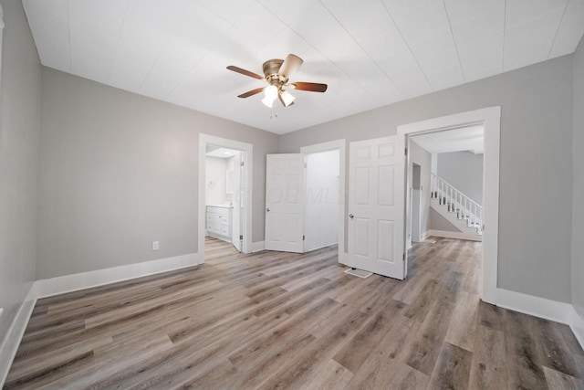 unfurnished bedroom with baseboards, ensuite bathroom, visible vents, ceiling fan, and wood finished floors