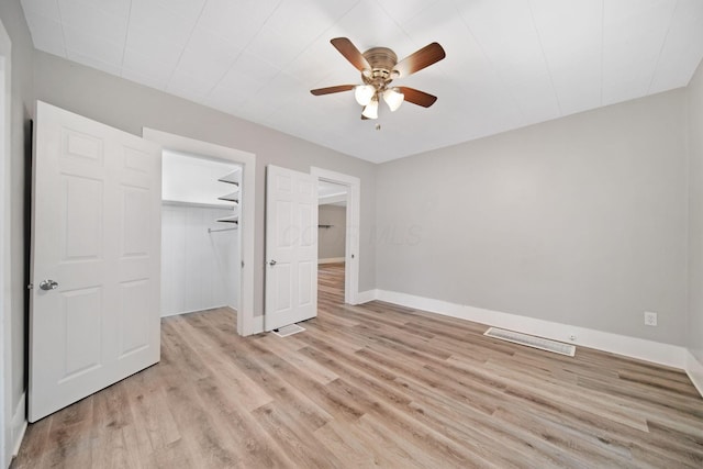 unfurnished bedroom with a closet, a ceiling fan, visible vents, light wood finished floors, and baseboards