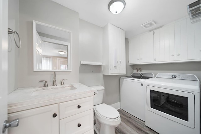 bathroom featuring vanity, visible vents, toilet, wood finished floors, and washing machine and clothes dryer