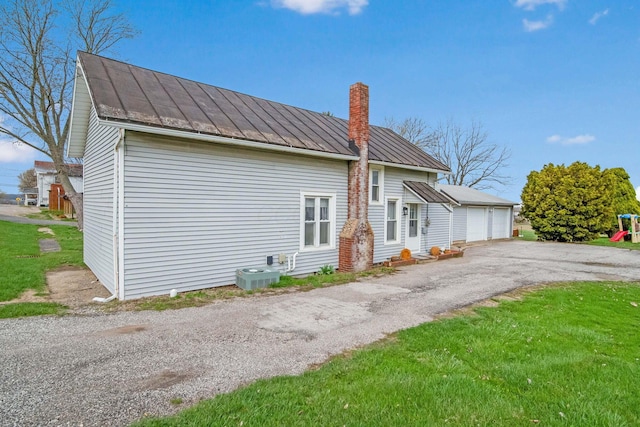 view of front of home featuring a standing seam roof, metal roof, a chimney, and a detached garage