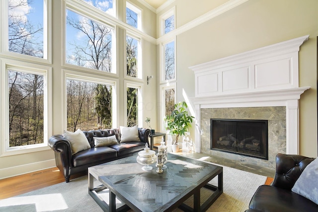 6795 Macneil Dr, Dublin, OH 43017 - living room featuring a towering ceiling, baseboards, ornamental molding, a fireplace, and light wood finished floors