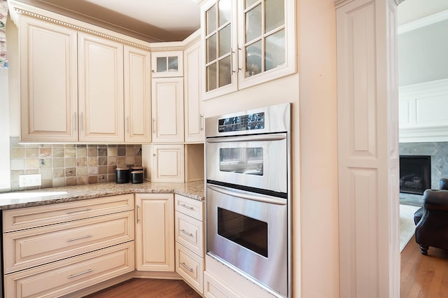 6795 Macneil Dr, Dublin, OH 43017 - kitchen featuring double oven, wood finished floors, light stone countertops, decorative backsplash, and cream cabinets
