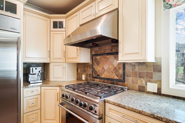 6795 Macneil Dr, Dublin, OH 43017 - kitchen with cream cabinetry, decorative backsplash, high quality appliances, and under cabinet range hood