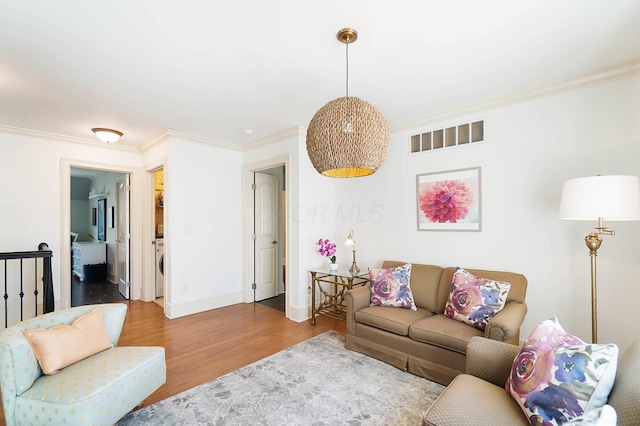 6795 Macneil Dr, Dublin, OH 43017 - living area with washer / clothes dryer, baseboards, ornamental molding, visible vents, and wood finished floors