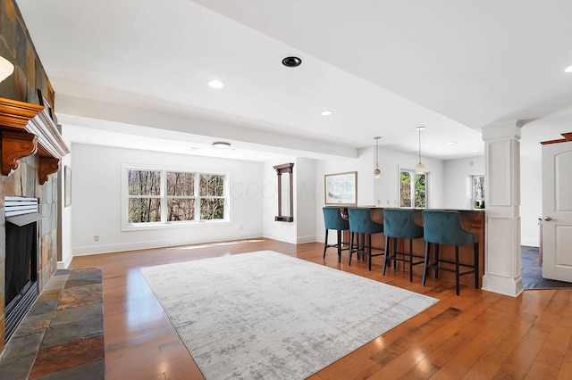 6795 Macneil Dr, Dublin, OH 43017 - interior space with baseboards, a fireplace, a breakfast bar area, decorative columns, and wood-type flooring