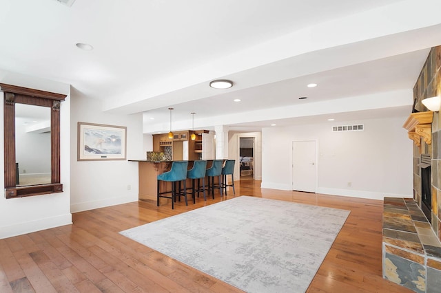 6795 Macneil Dr, Dublin, OH 43017 - living area with indoor bar, visible vents, a tiled fireplace, recessed lighting, and hardwood / wood-style floors