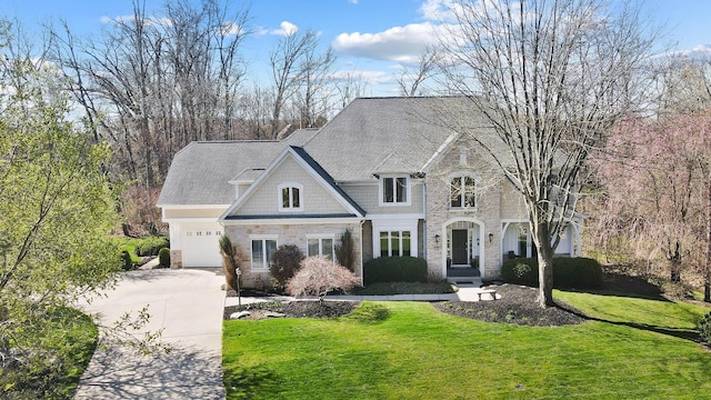 6795 Macneil Dr, Dublin, OH 43017 - view of front of home with a front yard, stone siding, a garage, and concrete driveway