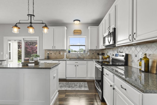 kitchen featuring dark wood-style flooring, a center island, white cabinets, a sink, and appliances with stainless steel finishes