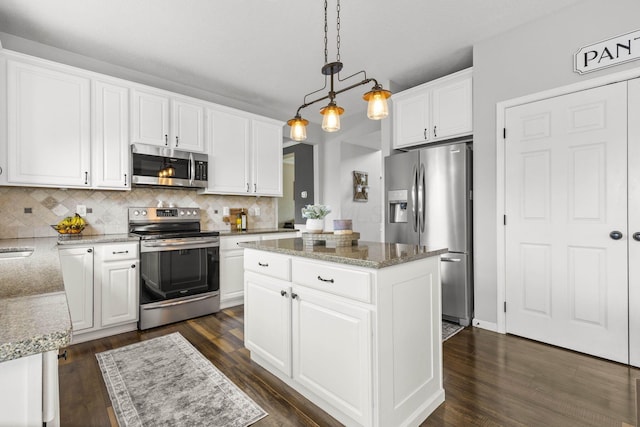 kitchen featuring dark wood-style flooring, a kitchen island, white cabinetry, tasteful backsplash, and appliances with stainless steel finishes