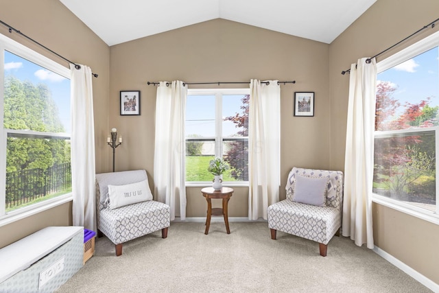 sitting room with baseboards, plenty of natural light, light carpet, and vaulted ceiling