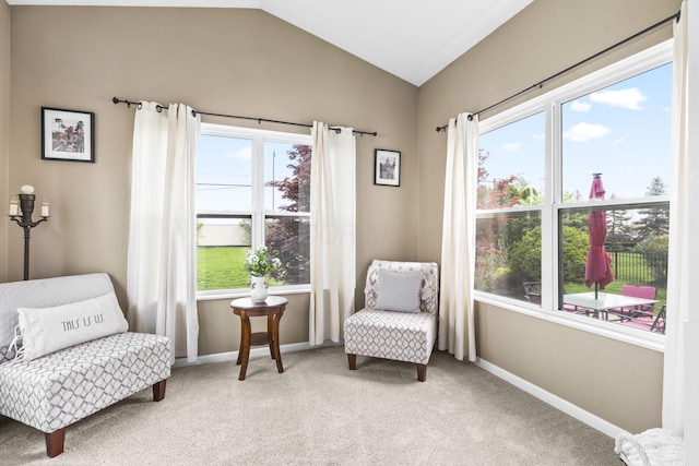 living area featuring baseboards, light carpet, and vaulted ceiling