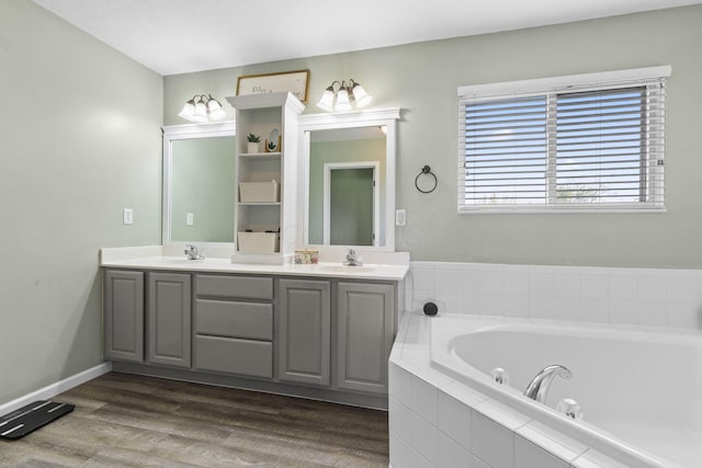 bathroom with a sink, double vanity, a bath, and wood finished floors