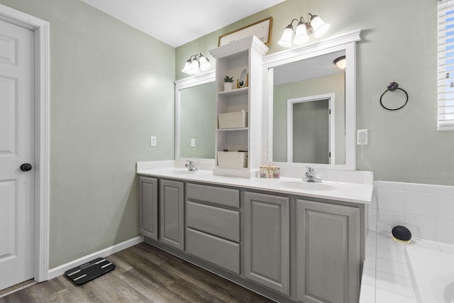 full bathroom featuring a sink, a tub to relax in, double vanity, and wood finished floors