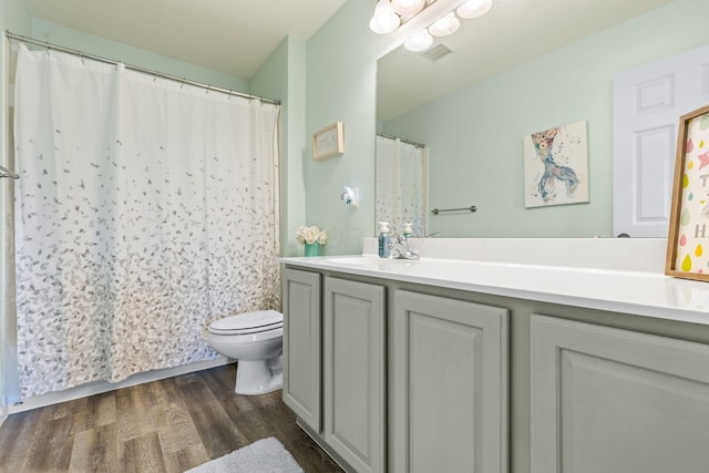 bathroom with visible vents, vanity, curtained shower, wood finished floors, and toilet
