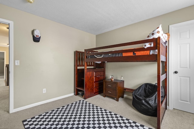 bedroom featuring baseboards, light carpet, and a textured ceiling