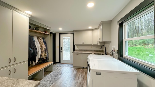clothes washing area featuring recessed lighting, light wood-style floors, cabinet space, washer and dryer, and a sink