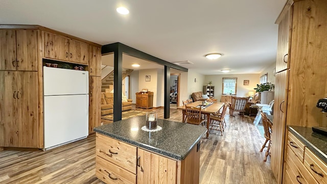 kitchen with open floor plan, freestanding refrigerator, light brown cabinetry, and light wood finished floors