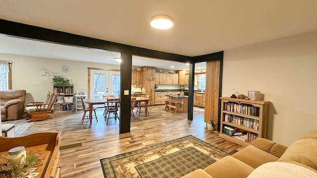 living area with light wood-style floors and beamed ceiling