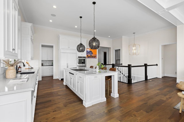 kitchen with white cabinets, a sink, dark wood finished floors, cooktop, and a breakfast bar area