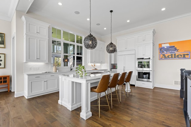 kitchen featuring backsplash, double oven, white cabinetry, and a sink