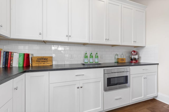kitchen featuring dark countertops, tasteful backsplash, and white cabinetry