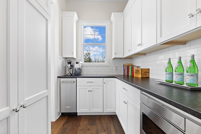 kitchen featuring stainless steel microwave, dark countertops, and white cabinets