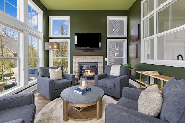 living area with a brick fireplace and wood finished floors