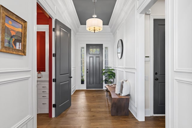 foyer with ornamental molding, a decorative wall, and dark wood-style flooring