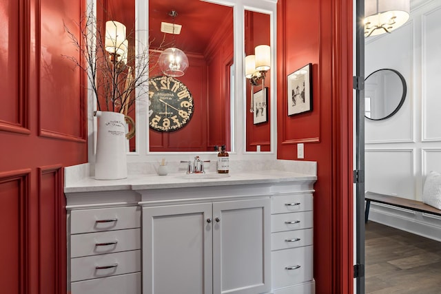bathroom with wood finished floors, crown molding, and vanity