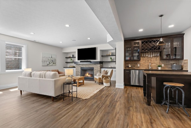 living room with recessed lighting, wet bar, dark wood-type flooring, baseboards, and a fireplace