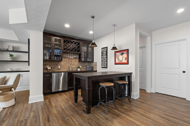 bar featuring dark wood finished floors, wet bar, dishwashing machine, and decorative backsplash