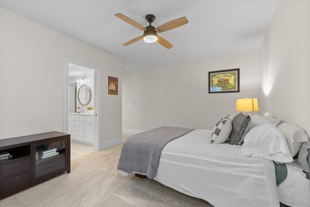 bedroom with a ceiling fan, light colored carpet, and connected bathroom