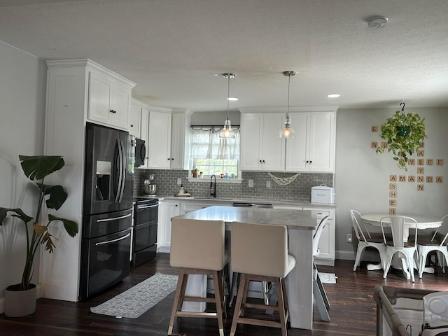 kitchen featuring dark wood finished floors, tasteful backsplash, white cabinetry, black appliances, and a kitchen island