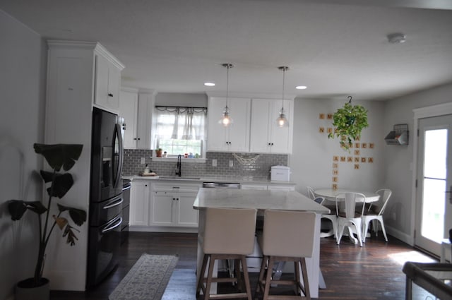 kitchen featuring a sink, a healthy amount of sunlight, black fridge, and dark wood finished floors