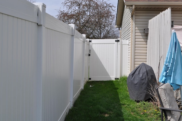 view of side of property with a yard, fence, and a gate