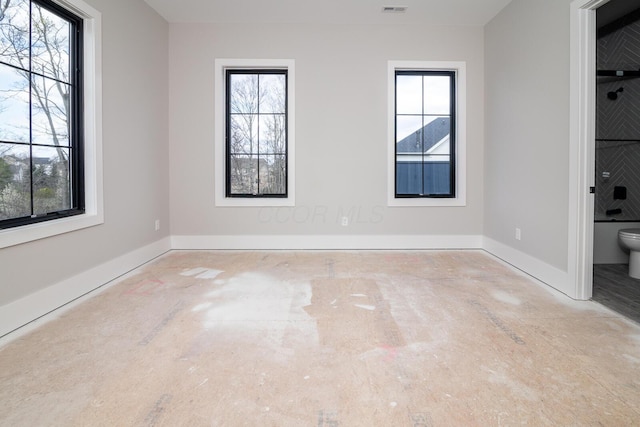 spare room with baseboards and a healthy amount of sunlight