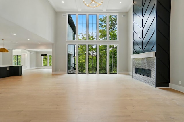 10007 Allen Dr, Dublin, OH 43017 - unfurnished living room featuring a glass covered fireplace, a chandelier, light wood-style floors, baseboards, and a high ceiling