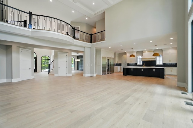 10007 Allen Dr, Dublin, OH 43017 - unfurnished living room with light wood-type flooring, stairway, a towering ceiling, baseboards, and recessed lighting