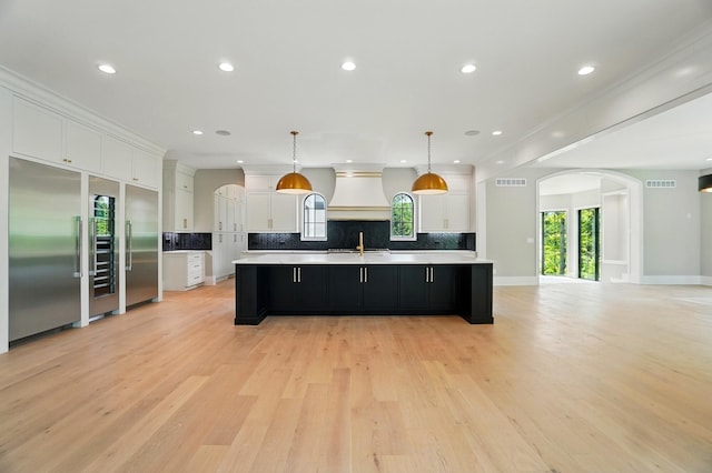 10007 Allen Dr, Dublin, OH 43017 - kitchen with arched walkways, a spacious island, custom range hood, open floor plan, and recessed lighting