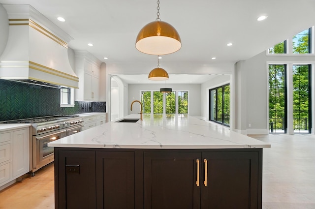 10007 Allen Dr, Dublin, OH 43017 - kitchen with range with two ovens, custom exhaust hood, a sink, backsplash, and a center island with sink