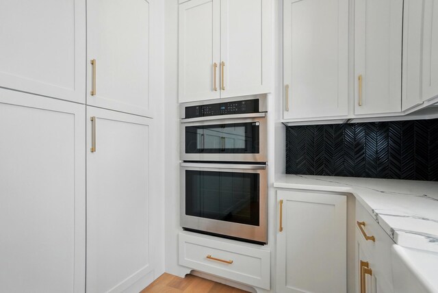 10007 Allen Dr, Dublin, OH 43017 - kitchen featuring stainless steel double oven, backsplash, light stone counters, and white cabinets