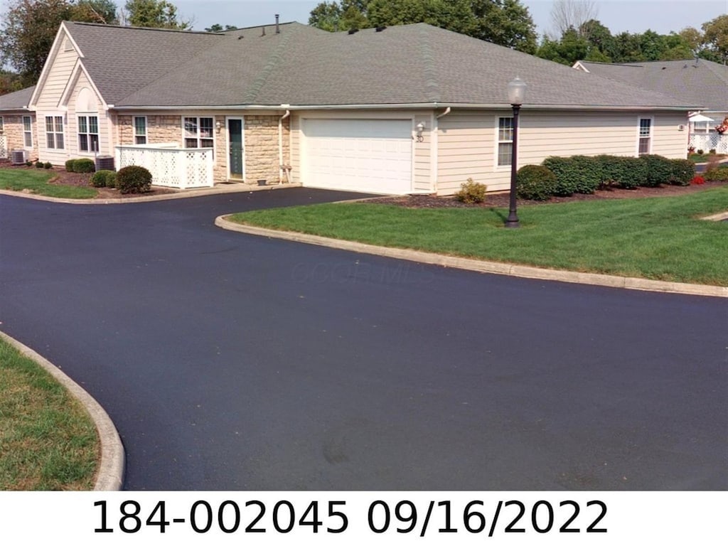 185 Groveport Pike Unit 3D, Canal Winchester, OH 43110 - view of front facade with an attached garage, driveway, a front lawn, central AC, and stone siding